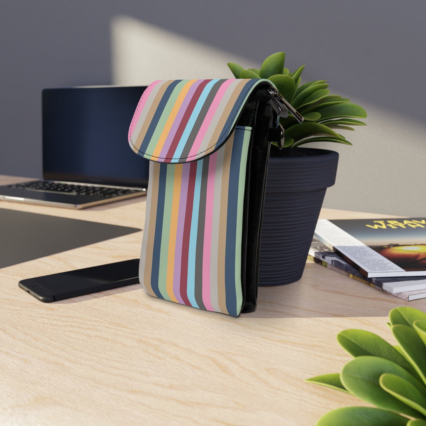 Eras TSwift Stripes Cell Phone Wallet Bag with colorful vertical stripes placed on wooden desk near plant and laptop
