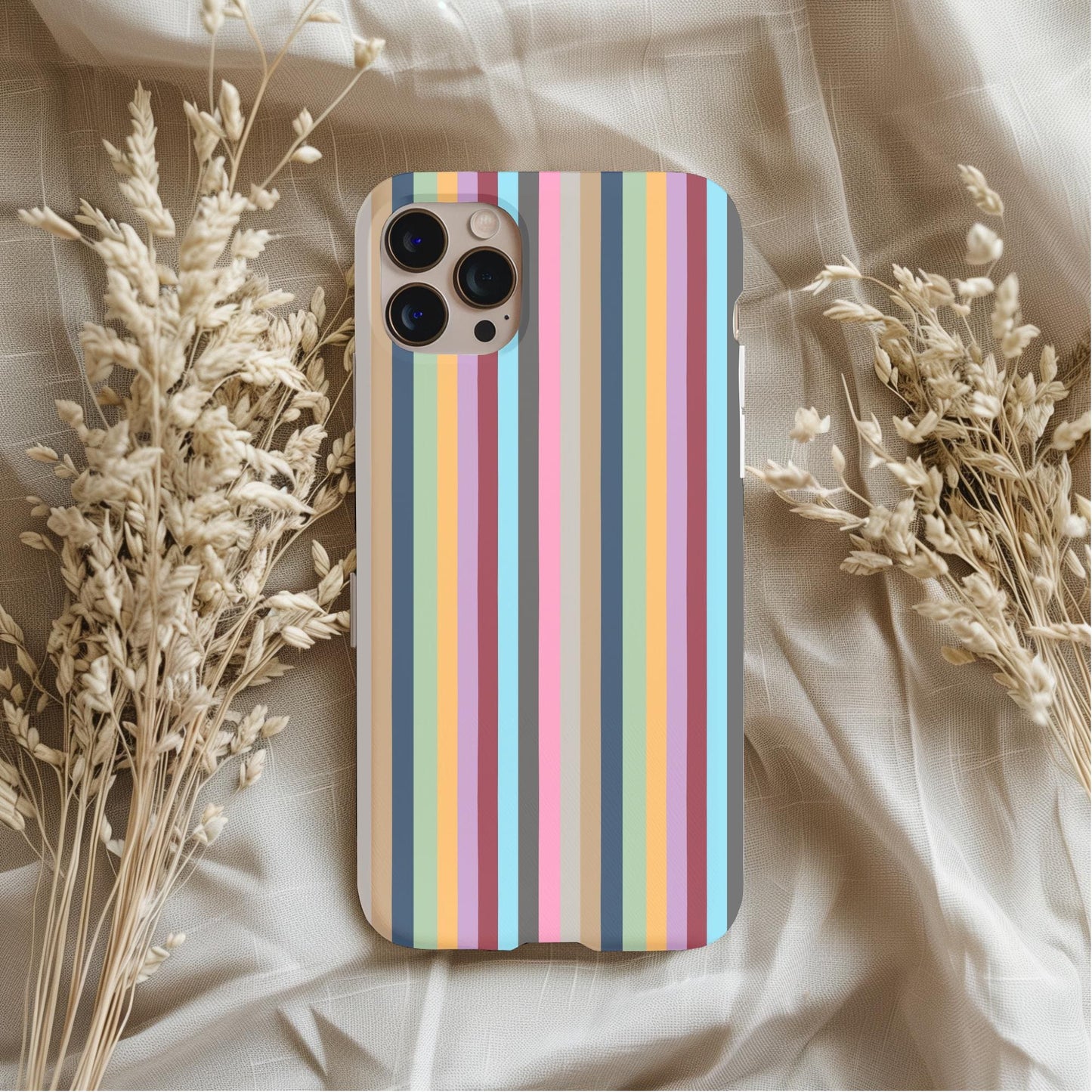 Taylor Swift Eras Stripes Phone Case featuring colorful vertical stripes placed on a soft beige fabric with dried flowers.