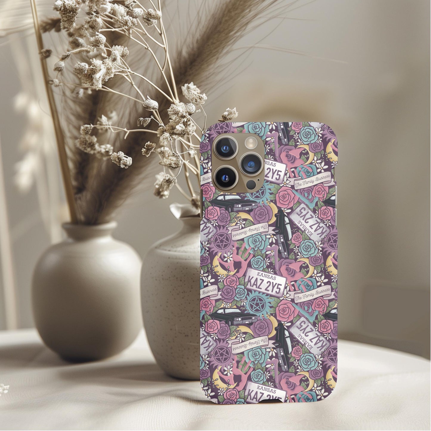 Supernatural Winchester Bros Floral Phone Case with intricate floral and emblem design on a smartphone against neutral vases background