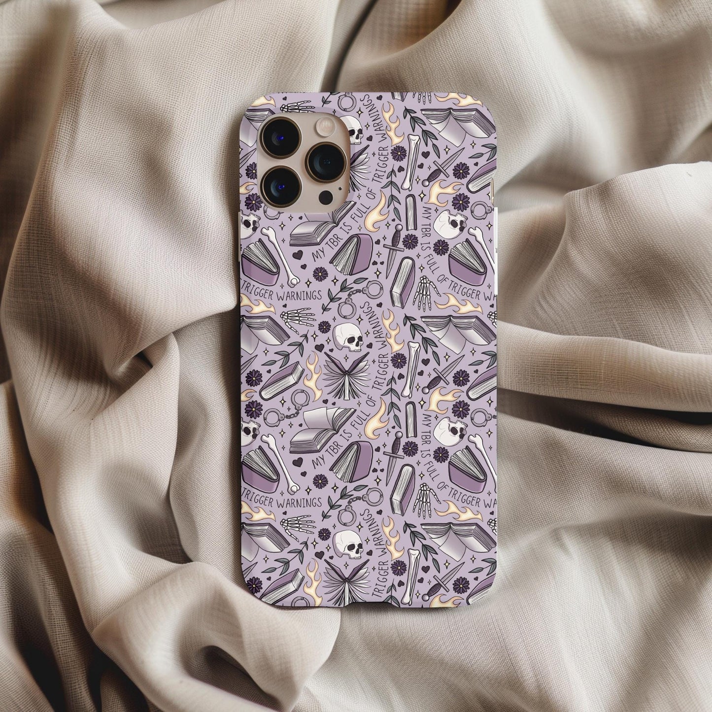 TBR Trigger Warning Bookish Phone Case with purple skull and book pattern on a beige fabric background