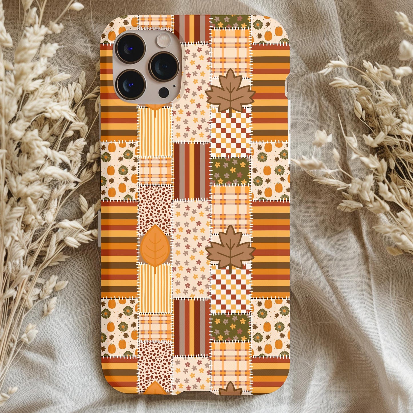 Autumn Pumpkin Patchwork Phone Case with warm fall colors and leaf patterns on a cozy fabric background.
