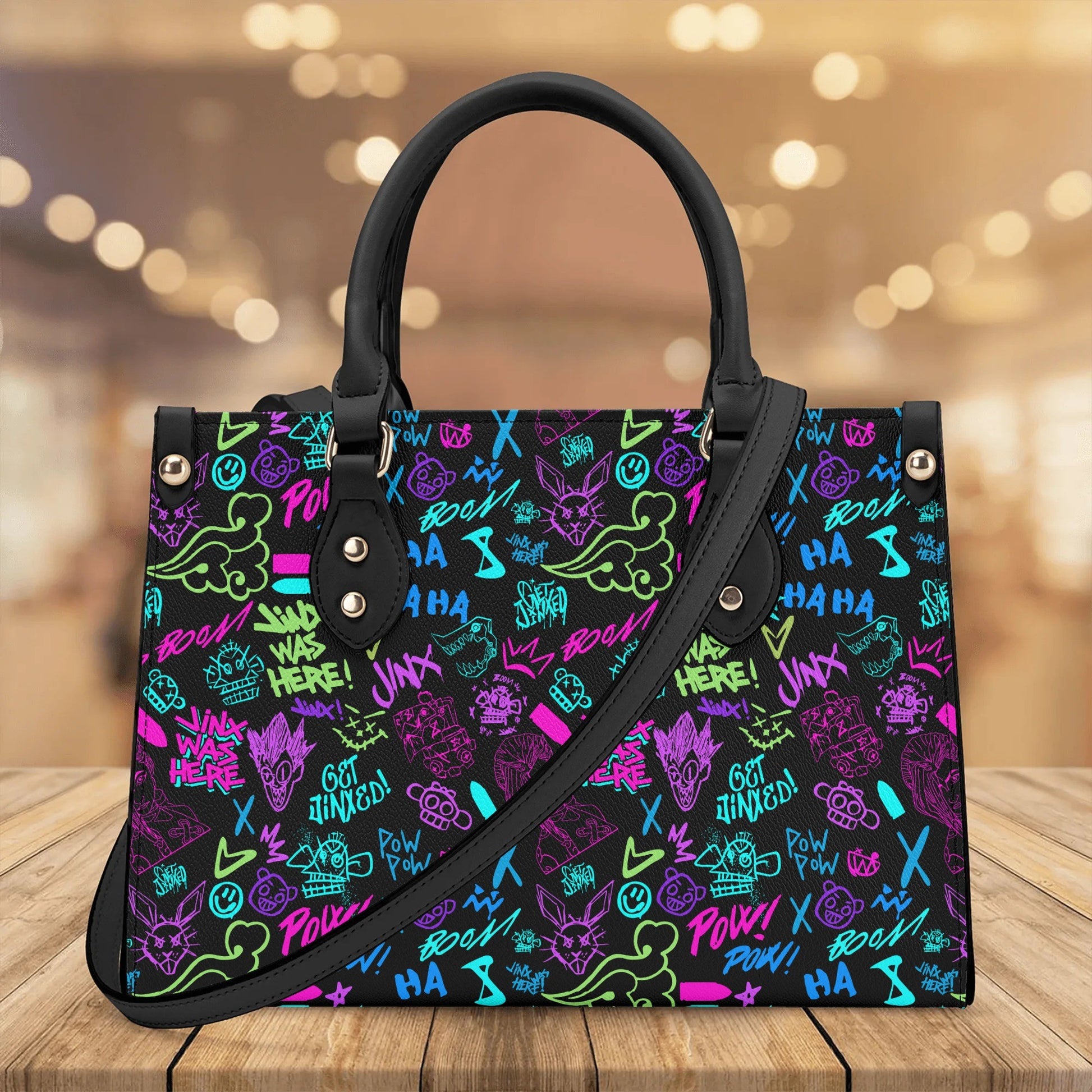 Arcane Jinx Graffiti Leather Handbag with colorful graffiti design and black handles on wooden surface background