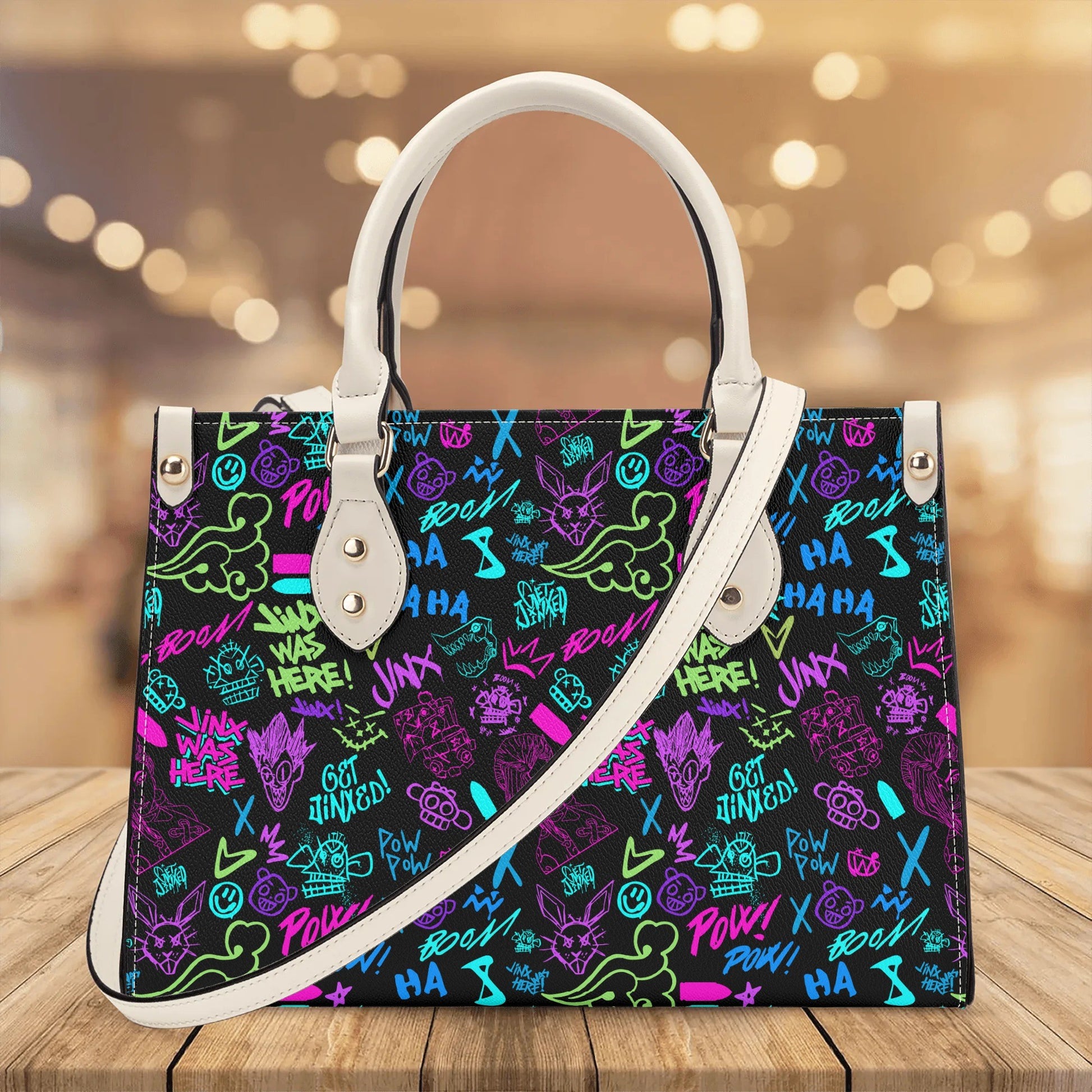 Arcane Jinx Graffiti Leather Handbag with vibrant colorful street art design and white leather straps on wooden surface