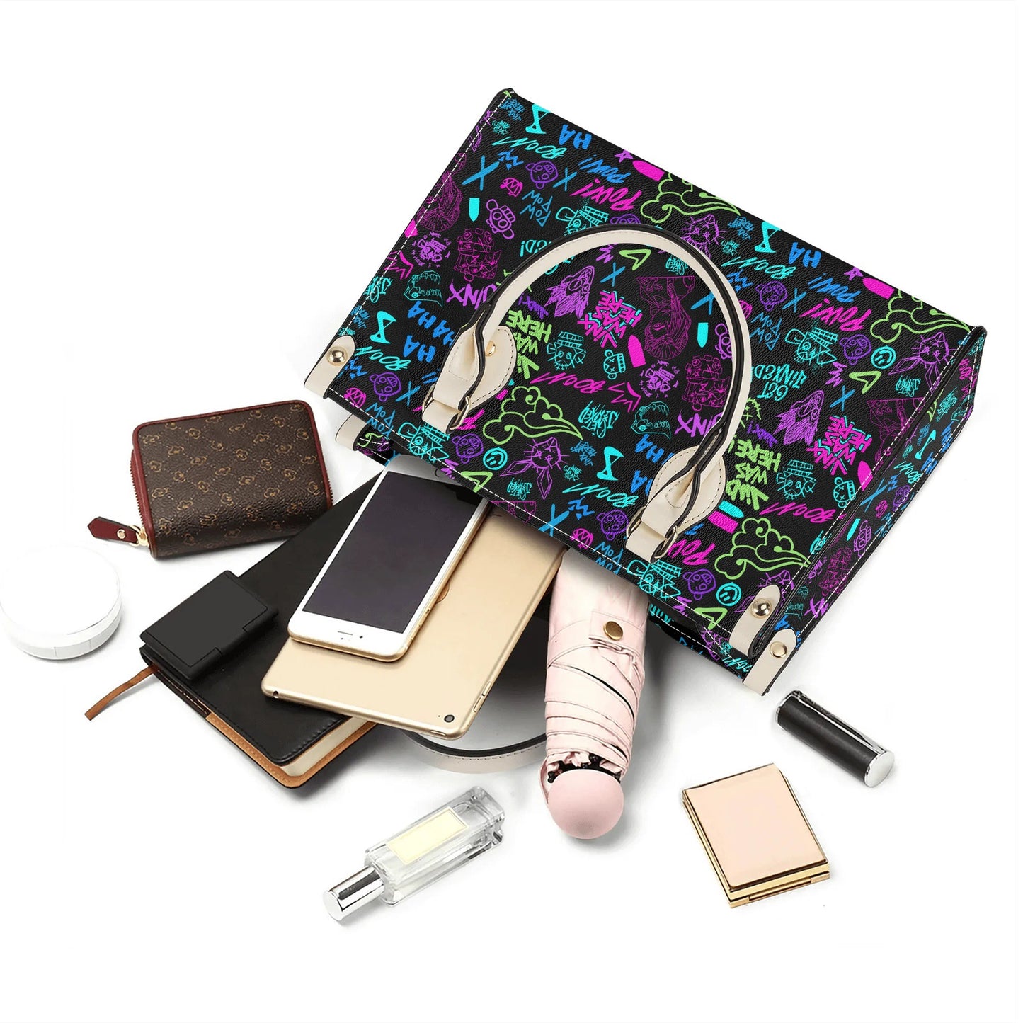 Arcane Jinx Graffiti Leather Handbag with colorful graffiti design and cream handles stylishly displayed with personal items