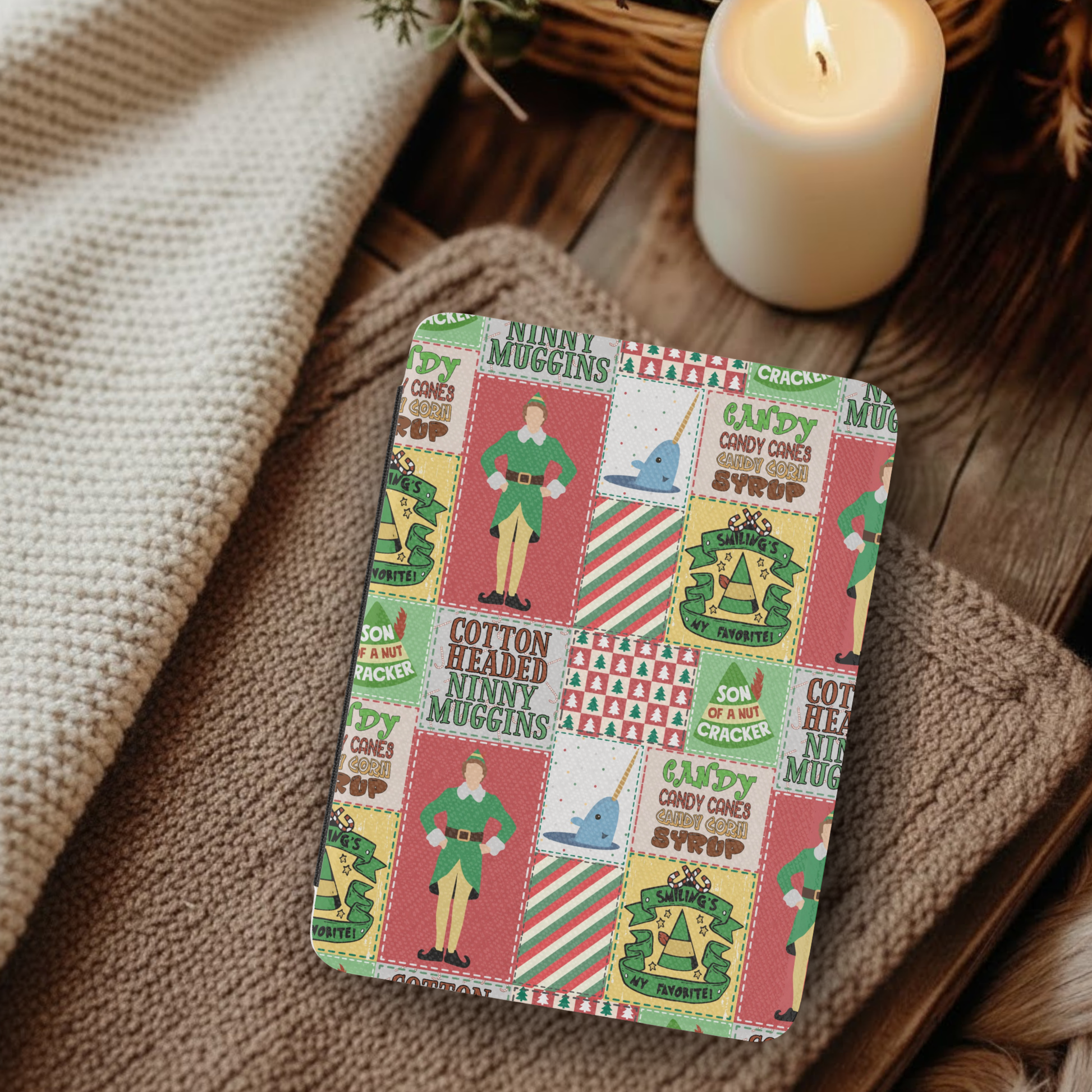 Christmas Elf Patchwork Leather Kindle Case with Hand Strap resting on cozy blankets near a lit candle on wooden surface