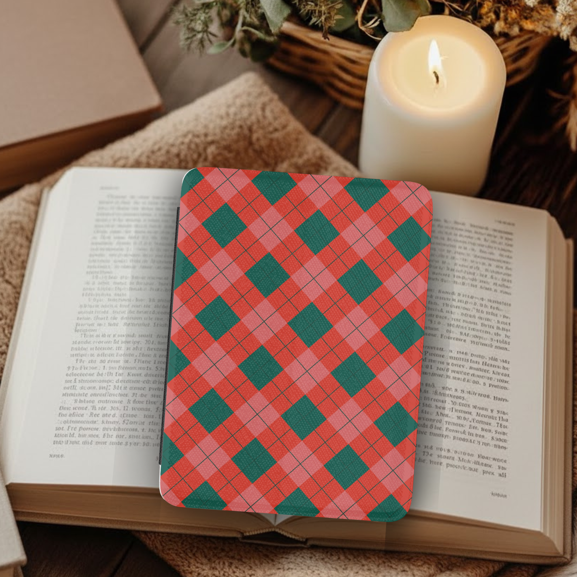 Classic Christmas Plaid Leather Kindle Case with Hand Strap displayed on an open book beside a lit candle and cozy decor.