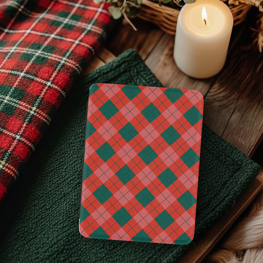 Classic Christmas Plaid Leather Kindle Case with Hand Strap resting on green fabric near candle and festive red plaid cloth