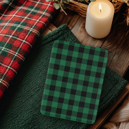 Green Buffalo Plaid Leather Kindle Case with Hand Strap displayed on green fabric near cozy candle and plaid cloth