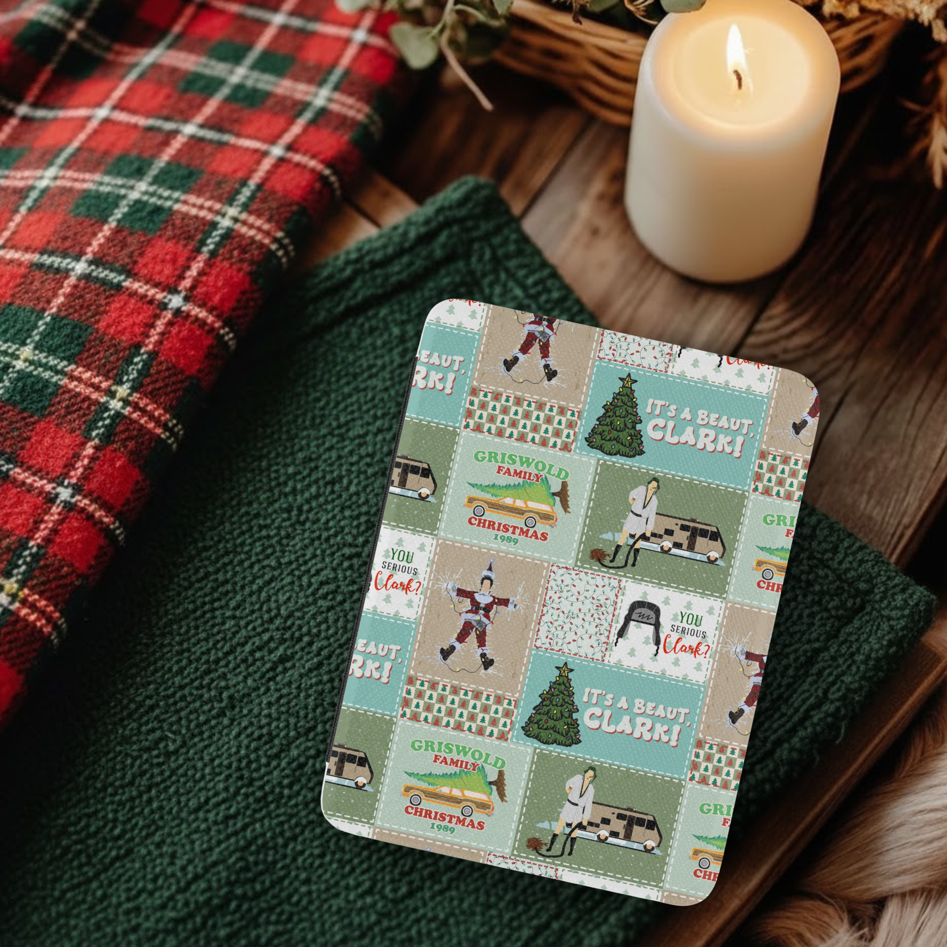 Christmas Vacation Patchwork Leather Kindle Case with Hand Strap on cozy fabric next to lit candle and plaid textile